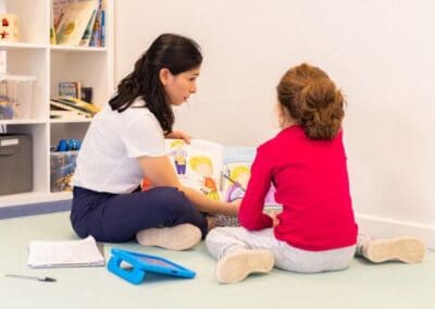 A therapy session with therapist showing and reading a book to little autistic girl
