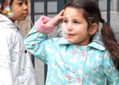 Picture of two autistic little girls, looking happy and smiling at bubbles flying in the air