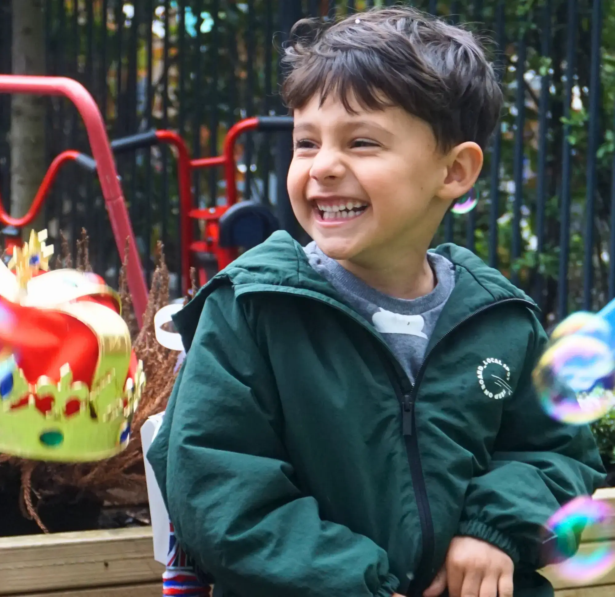 Autistic child excited and smiling at his therapist at a small gathering with bubbles all around him