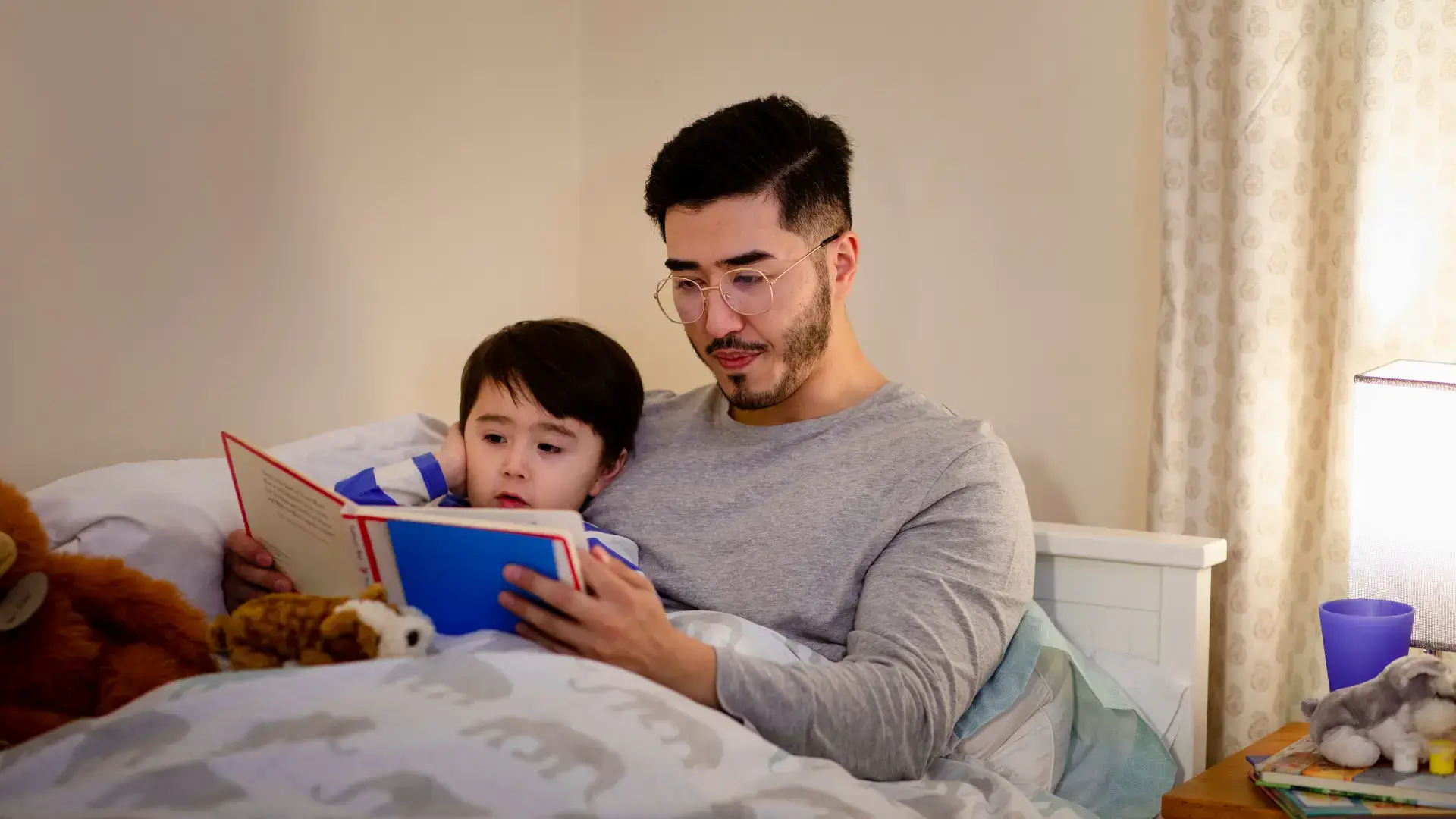 Dad reading a book to his son before bedtime