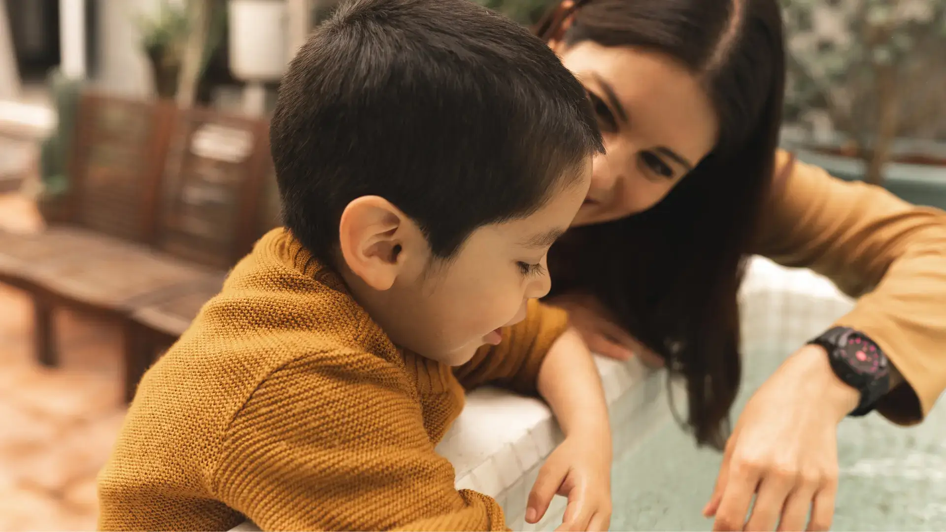 An autistic child playing with water and having fun with his mom