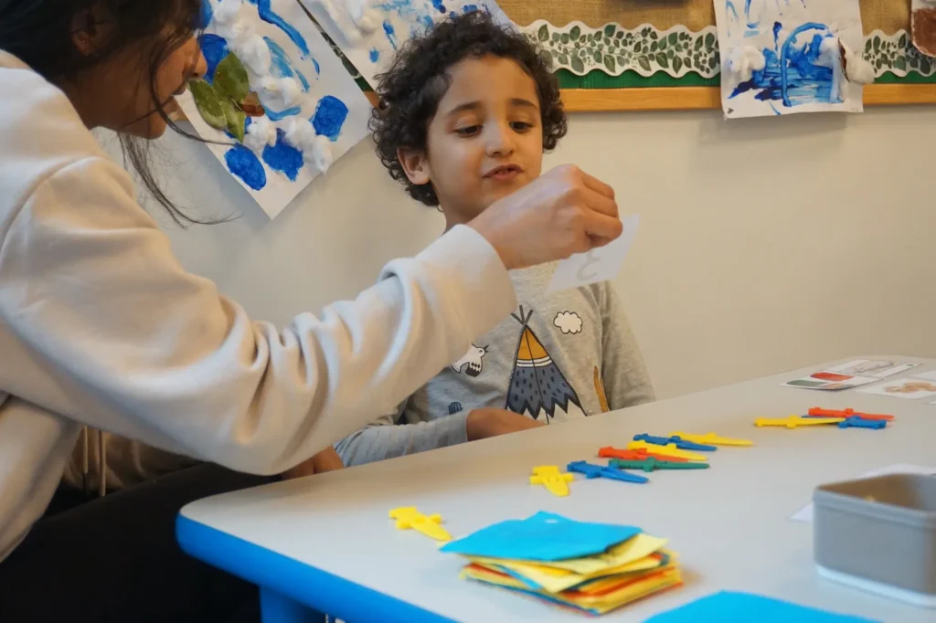 An autistic little boy during therapy at school, identifying numbers and associating them with objects