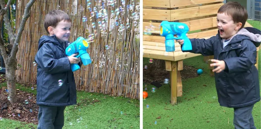 A little boy having fun with a bubble machine, looking very excited and happy