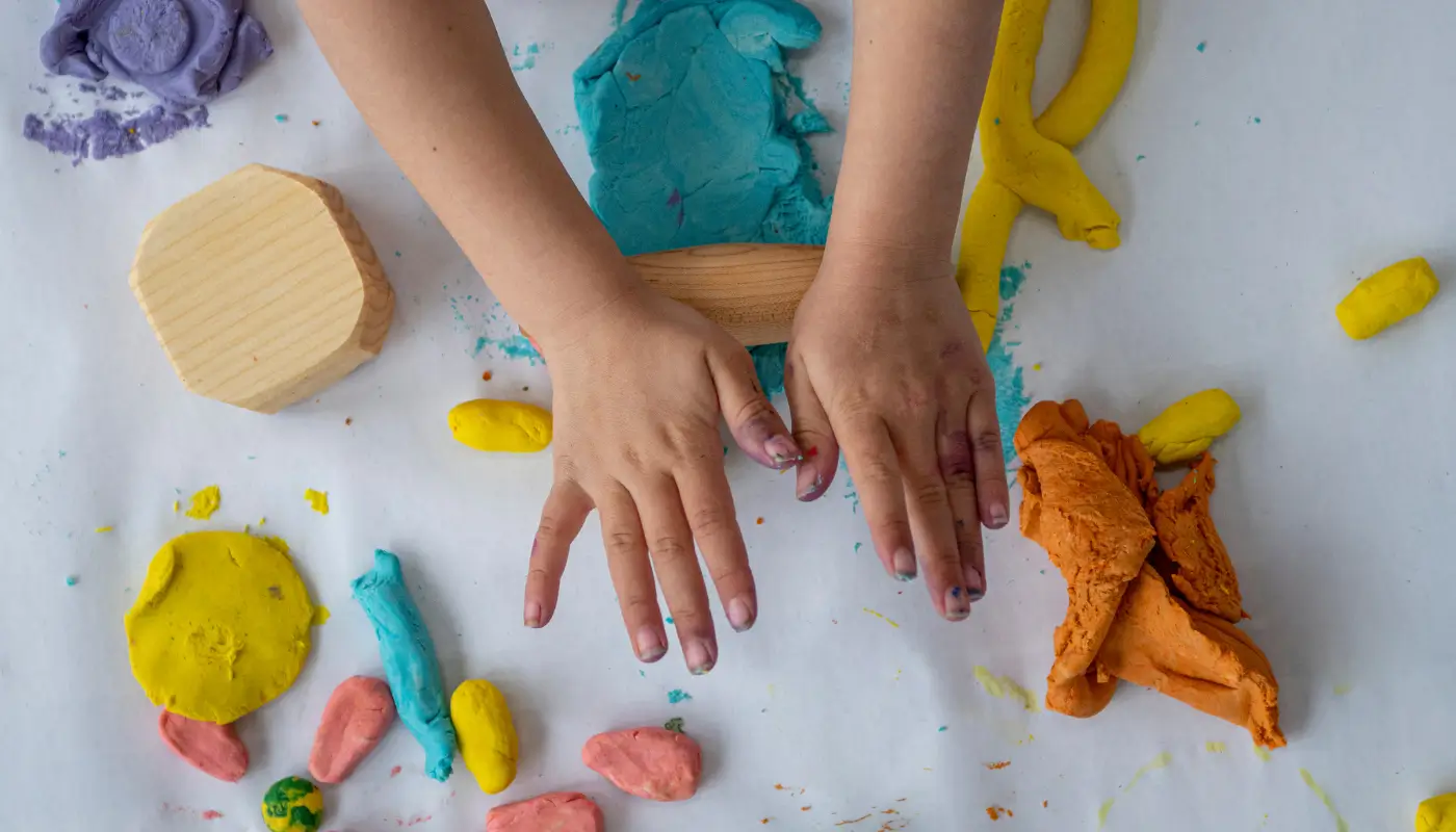 A picture of a child's hands playing with playdough on a table