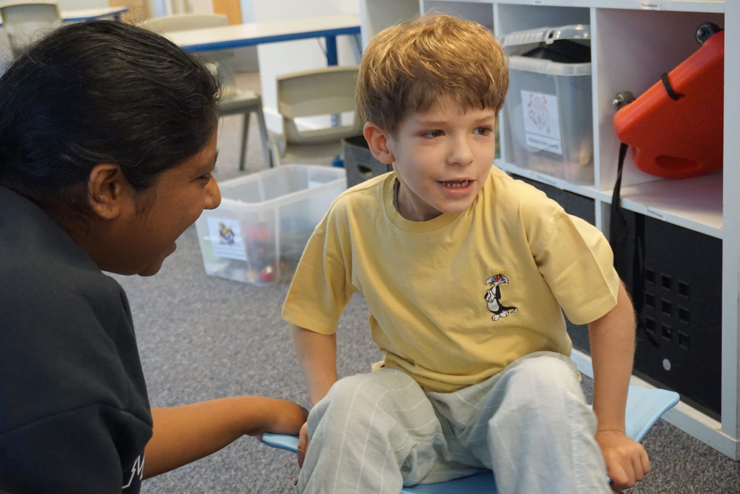A smiling child at First Bridge School is engaging with a teacher at First Bridge School, a specialist SEN school for autism, highlighting personalised support and inviting families to attend their virtual open day.